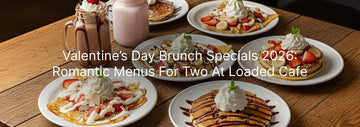 A romantic Valentine’s Day brunch spread at Loaded Cafe with pancakes, crepes, waffles topped with strawberries and whipped cream, served alongside milkshakes on a wooden table