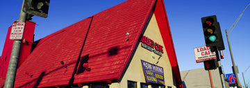 Exterior of Loaded Cafe with a red roof and vibrant signage displaying 'Loaded Cafe Pancakes & Burgers,' along with a 'Now Hiring' banner and nearby street signs.