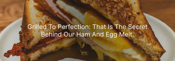 Grilled ham and egg melt sandwich with golden toasted bread, melted cheese, ham, and a runny egg yolk, with the text “Grilled To Perfection: That Is The Secret Behind Our Ham And Egg Melt.”
