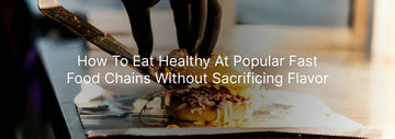 Close-up of a gloved hand preparing a gourmet burger on a counter, with the text “How To Eat Healthy At Popular Fast Food Chains Without Sacrificing Flavor”
