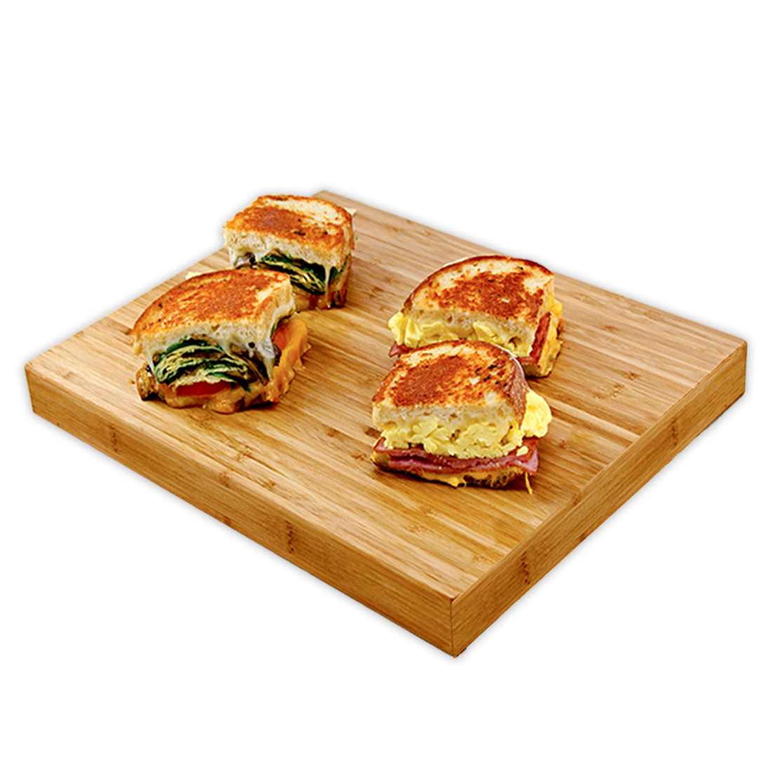 Grilled sandwich halves on a wooden board, with one filled with scrambled eggs, ham, and cheese, and the other with scrambled eggs, spinach, and tomato.